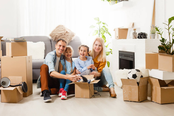 Familia feliz con cajas de cartón en casa nueva en el día de mudanza. - Foto, Imagen