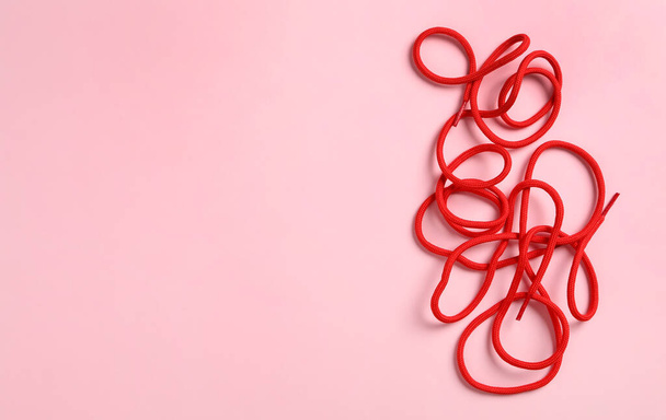 Red shoelaces on pink background, flat lay. Space for text - Foto, immagini