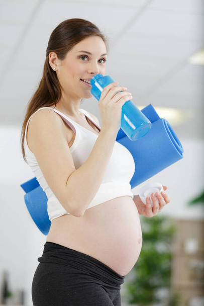 confident mother to be is drinking water after sport - Fotó, kép