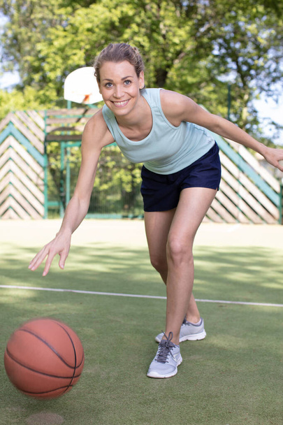 young woman playing basketball on street court - Zdjęcie, obraz
