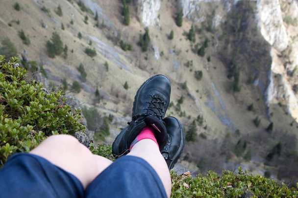 жіночі ноги в пішохідних черевиках, що сидять на вершині гори
 - Фото, зображення