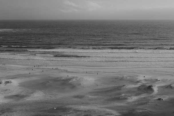 A grayscale shot of people at the sandy beach - Fotó, kép