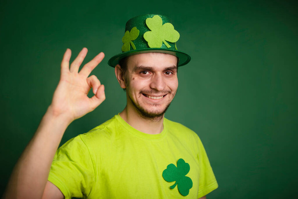 Un hombre con un sombrero de trébol y una camiseta verde se ve bien. El tipo está celebrando el día de San Patricio. Estudio foto - Foto, imagen