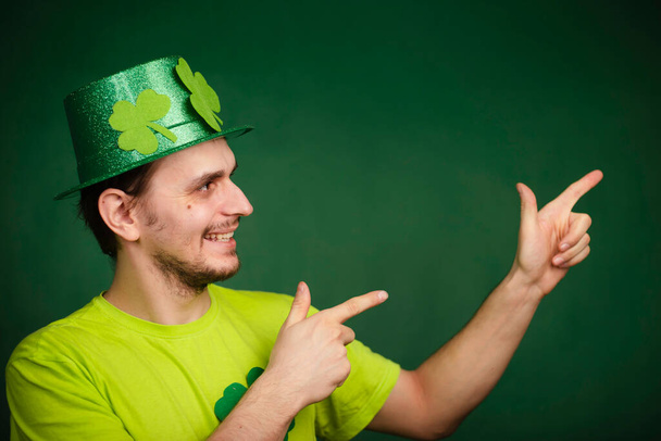 Shamrock-hattu ja vihreä t-paita osoittavat etusormea ylöspäin. Hän juhlii Pyhän Patrickin päivää. studio - Valokuva, kuva