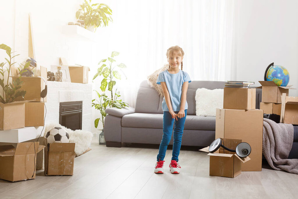 Little girl moving into new house, near cardboard box. - Photo, Image