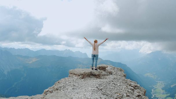 Młoda kobieta z wyciągniętymi ramionami ciesząca się pięknem natury na skale górskiej - Zdjęcie, obraz