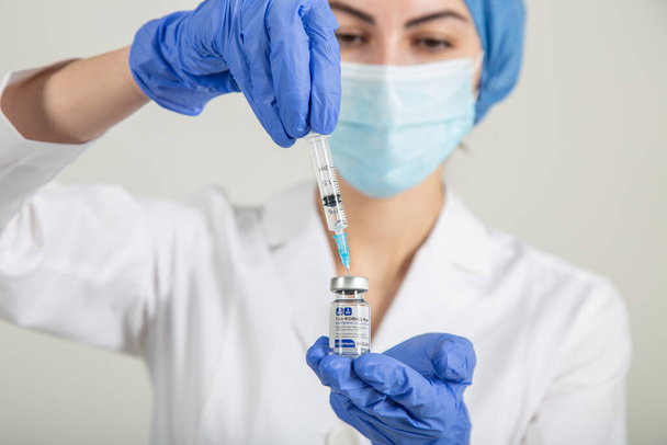 Nurse or doctor in medical uniform with Russian coronavirus vaccine Sputnik V and syringe - Fotó, kép