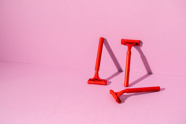 Red disposable razor on pink background, copy space - Фото, изображение