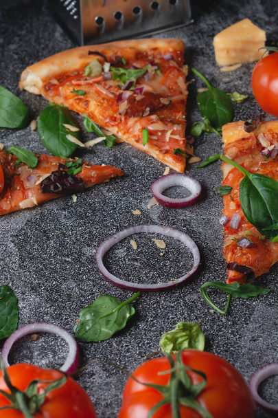 Traditionelle italienische Pfefferoni-Pizza mit Tomaten, Käse, Zwiebeln und vielen Kräutern auf einer dunklen Schiefertafel - Foto, Bild