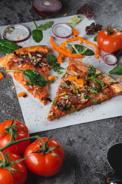 Hausgemachte italienische Pizza mit Paprika, Tomaten, Käse, Zwiebeln und Kräutern auf hellem Backpapier - Foto, Bild