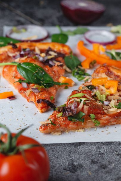 Hausgemachte italienische Pizza mit Paprika, Tomaten, Käse, Zwiebeln und Kräutern auf hellem Backpapier - Foto, Bild