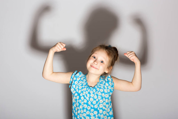 Little girl posing like a bodybuilder, raised her arms and flexed her biceps. - Фото, зображення