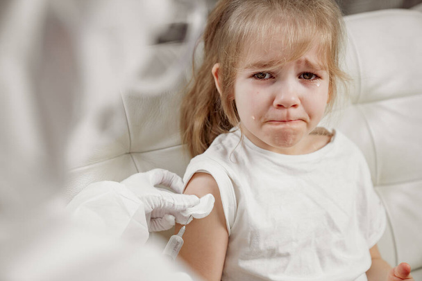 La niña llora herida y asustada. inyección. Vacunación. - Foto, Imagen