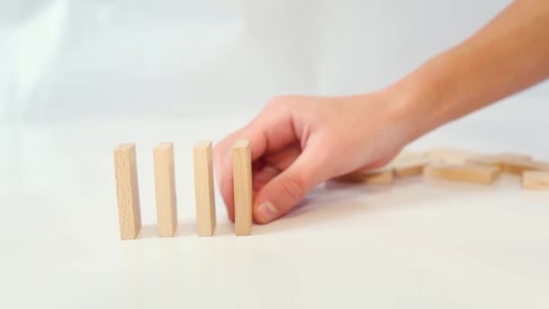 Spelen met dominostenen in een kettingreactie De jongen bouwt houten dominostenen in rij - Video