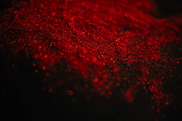 Red sand from sequins. Scattered sparkles on a black background. Space texture. - Zdjęcie, obraz