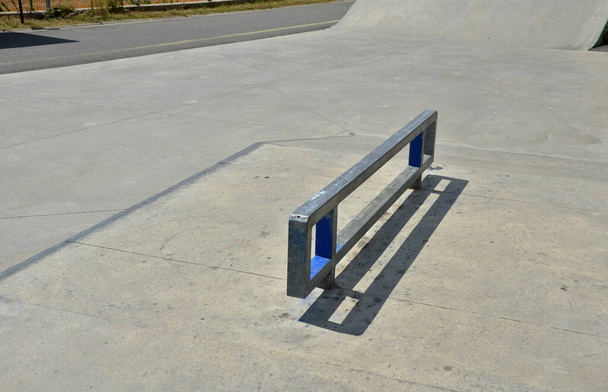бетонная площадка для скейтборда в огороженной местности за пределами города. Рейлинги предназначены для начинающих на скутерах, BMX-велосипедах и скейтбордах. волнистые области для тестирования прыжков и трюков - Фото, изображение
