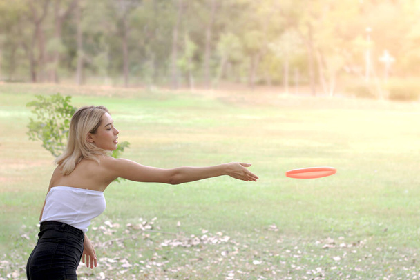 Feliz joven hermosa chica adolescente divirtiéndose con frisbee mientras pasa tiempo con un amigo en el jardín de verano.  - Foto, imagen