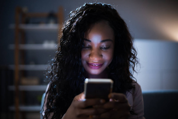 African Woman Using Mobile Phone Or Smartphone In Dark At Night - Fotografie, Obrázek