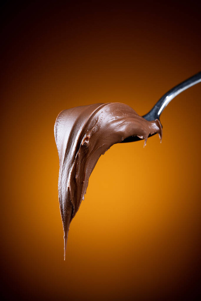 Tejszín csokoládé kanállal fekete háttér - Fotó, kép