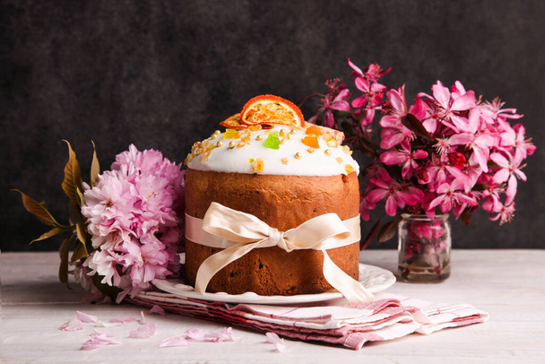 Gâteau de Pâques avec bouquet de fleurs roses sur fond de bois noir. - Photo, image
