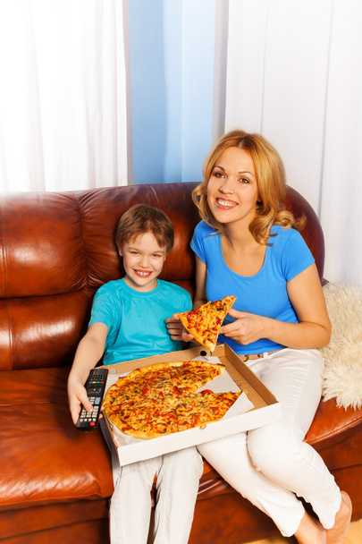 Poika ja hänen hymyilevä äitinsä syövät pizzaa
 - Valokuva, kuva