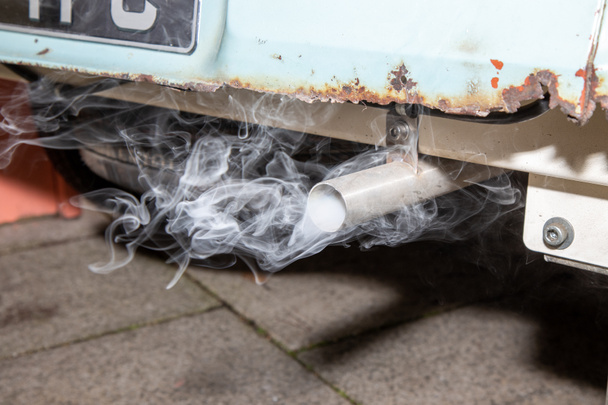 Egy füstölgő kipufogócső egy öreg rozsdás autóból. - Fotó, kép