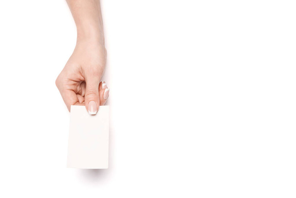 Female hand holding a blank business card over white background - Fotoğraf, Görsel