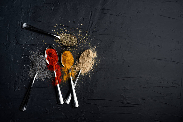 spices in metal spoon on black background - Photo, Image