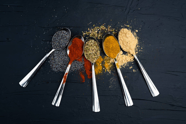 spices in metal spoon on black background - 写真・画像