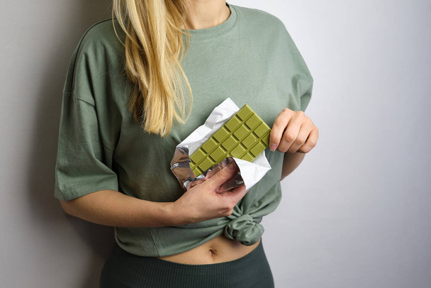 Chocolate with matcha in the hands of girl. Green bar of chocolate. Delicious sweet dessert. Cacao and Japanese green tea confection. Healthy vegetarian natural snack. Organic food. Chocolate closeup - Фото, изображение