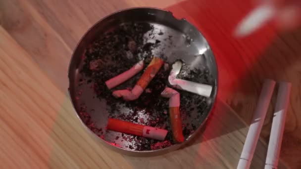 Een man in een bar doet een sigaret uit in een asbak en neemt een nieuwe sigaret - Video