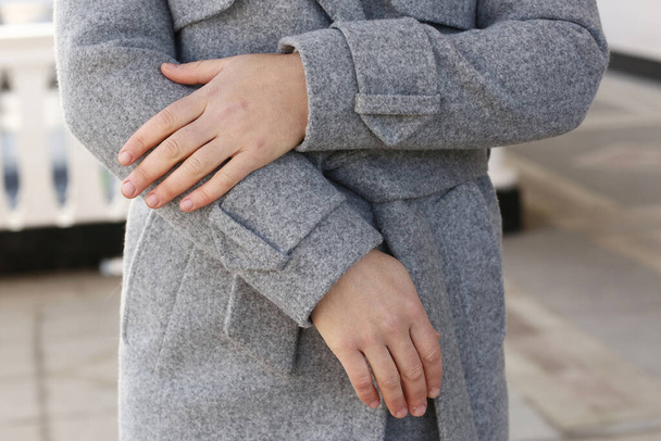 casaco de lã cinza close up detalhe com as mãos modelo no fundo da rua da cidade - Foto, Imagem
