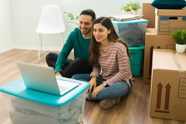 Супружеская пара сидит среди коричневых коробок и видео, обзванивая своих друзей и семью, чтобы показать им свой новый дом - Фото, изображение
