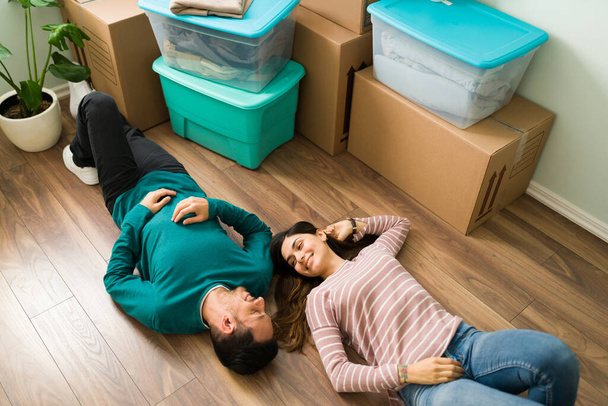 Verliebte Paare entspannen sich und machen nach dem Einzug eine Pause beim Auspacken der Kisten mit ihren Sachen und Möbeln - Foto, Bild