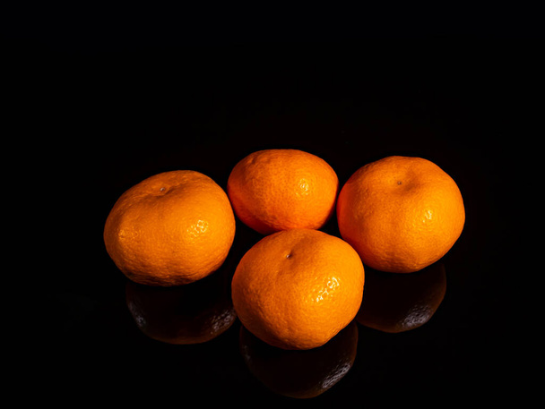Orange tangerine fruit on a black background. Orange tangerine. Green leaf. Fruit juice. Collection of garden citrus fruits. Agriculture. Vegetarian food. Photo of food. Background. - Photo, image