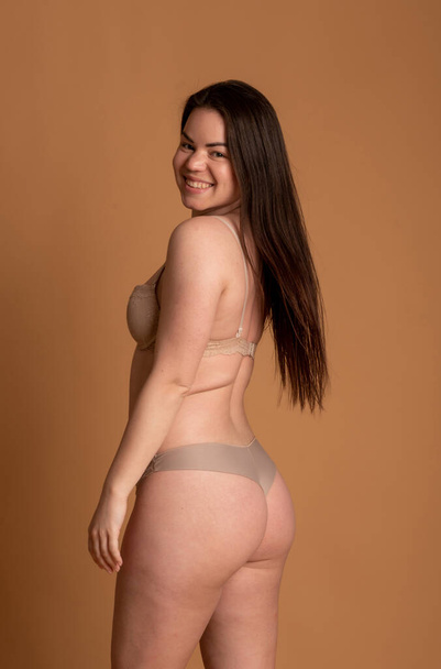Beautiful overweight woman in beige swimsuit on pink background - Foto, imagen
