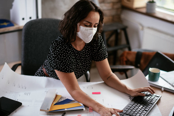 жінка працює в офісі, одягнена в захисну маску
 - Фото, зображення