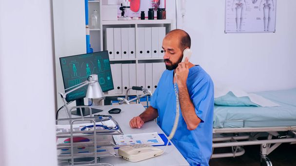 Erkek sağlık doktoru hastanede çalışan telefonlara cevap veriyor. - Fotoğraf, Görsel