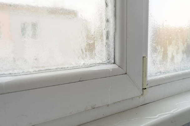 Закрыть дефектное пластиковое окно с конденсацией и замерзанием внутри. Плохая вентиляция, высокая влажность и разница температур. - Фото, изображение