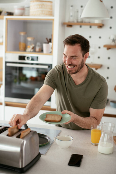 mladý krásný muž těší jeho čerstvé snídaně v dopoledních hodinách - Fotografie, Obrázek