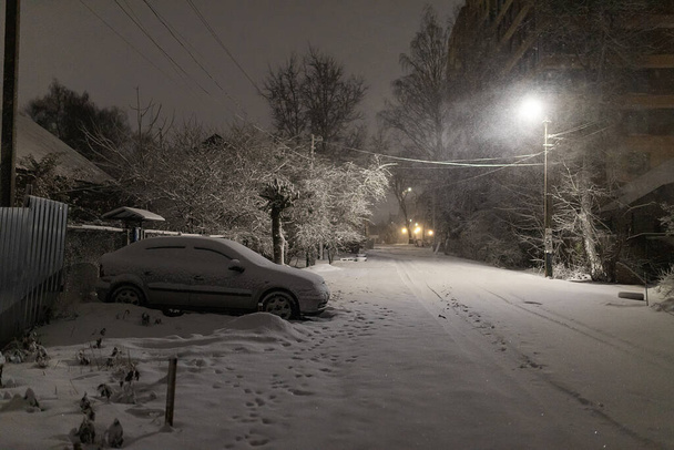 pod světlem pouličních lamp byla auta na parkovišti pokryta sněhem, problémy majitelů automobilů kvůli silné sněhové bouři, zimní sněhové závěje ve městě - Fotografie, Obrázek
