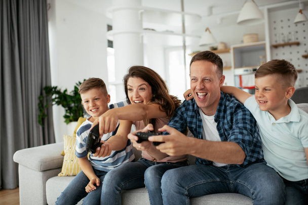 Férj és feleség videojátékoznak joystickokkal a nappaliban. Szerető pár videojátékot játszik a gyerekekkel otthon. - Fotó, kép
