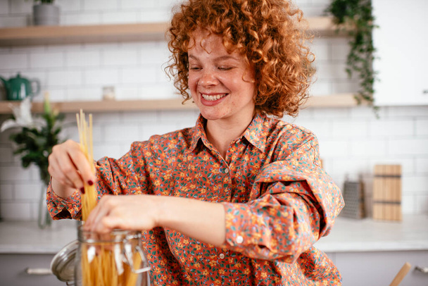 Beautiful woman with curly hair enjoying in the kitchen. - Фото, зображення