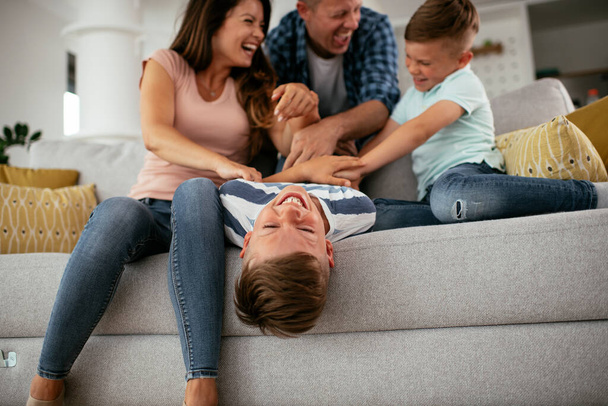 Молодая семья наслаждается дома. Счастливые родители с сыновьями веселятся. - Фото, изображение
