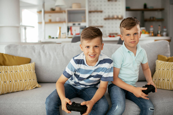brothers playing video games. Young brothers having fun while playing video games in living room. - Fotoğraf, Görsel