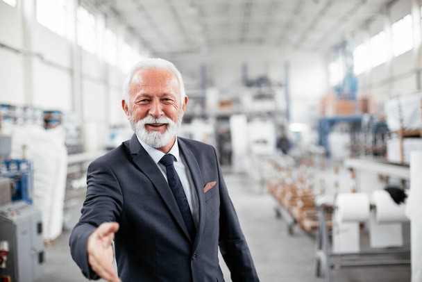 Portrait of handsome senior businessman. Man handshake in factory. - Foto, afbeelding