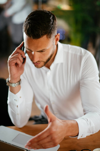 Бізнесмен обговорює роботу по телефону. Молодий бізнесмен розмовляє по телефону в офісі
. - Фото, зображення