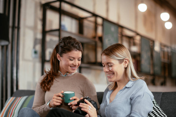 Счастливые деловые женщины разговаривают и смеются в открытом космосе. Женщины пьют кофе в офисе. - Фото, изображение