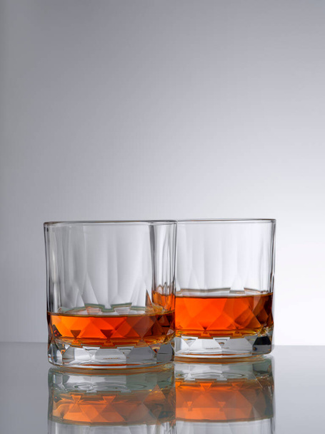 close up view of two glasses with ice and whiskey on grery background - Fotoğraf, Görsel