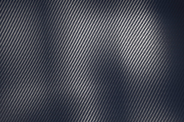 Detalle estructural de una lámina de fibra de carbono industrial en una vista de marco completo que muestra el patrón diagonal repetido mientras la luz juega a través de la superficie en una textura de fondo - Foto, imagen